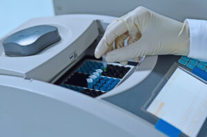 Scientist holding PCR tube put into PCR machine